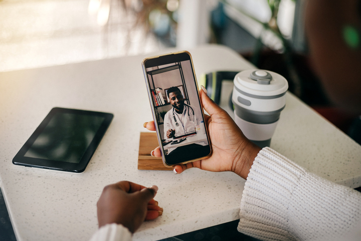 Young adult black woman on a video call with her doctor at home.