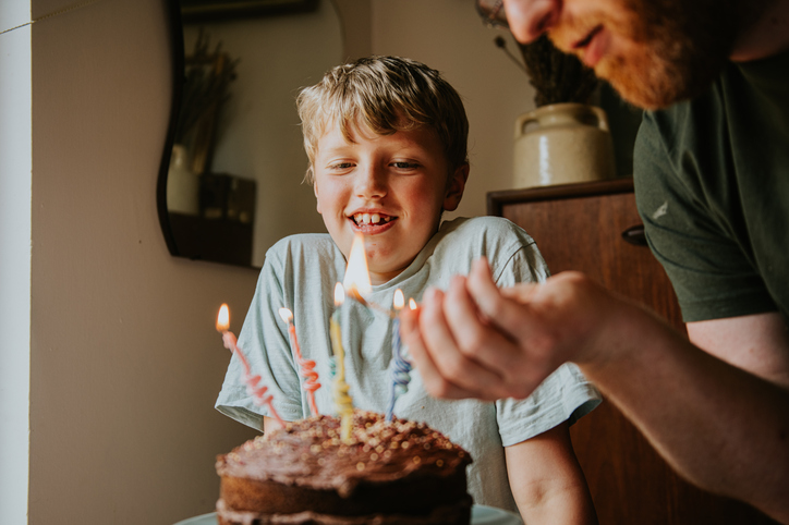 A father lights the birthday candles on his son’s birthday cake
